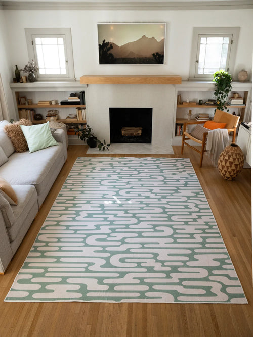 Green Abstract Wavy Area Rug centered in a bright modern living room between a cream sofa and fireplace