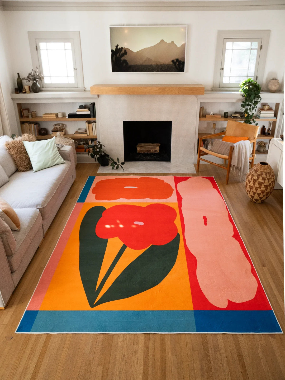 Abstract floral area rug stretched toward the fireplace, showing bold red and pale pink flower blocks