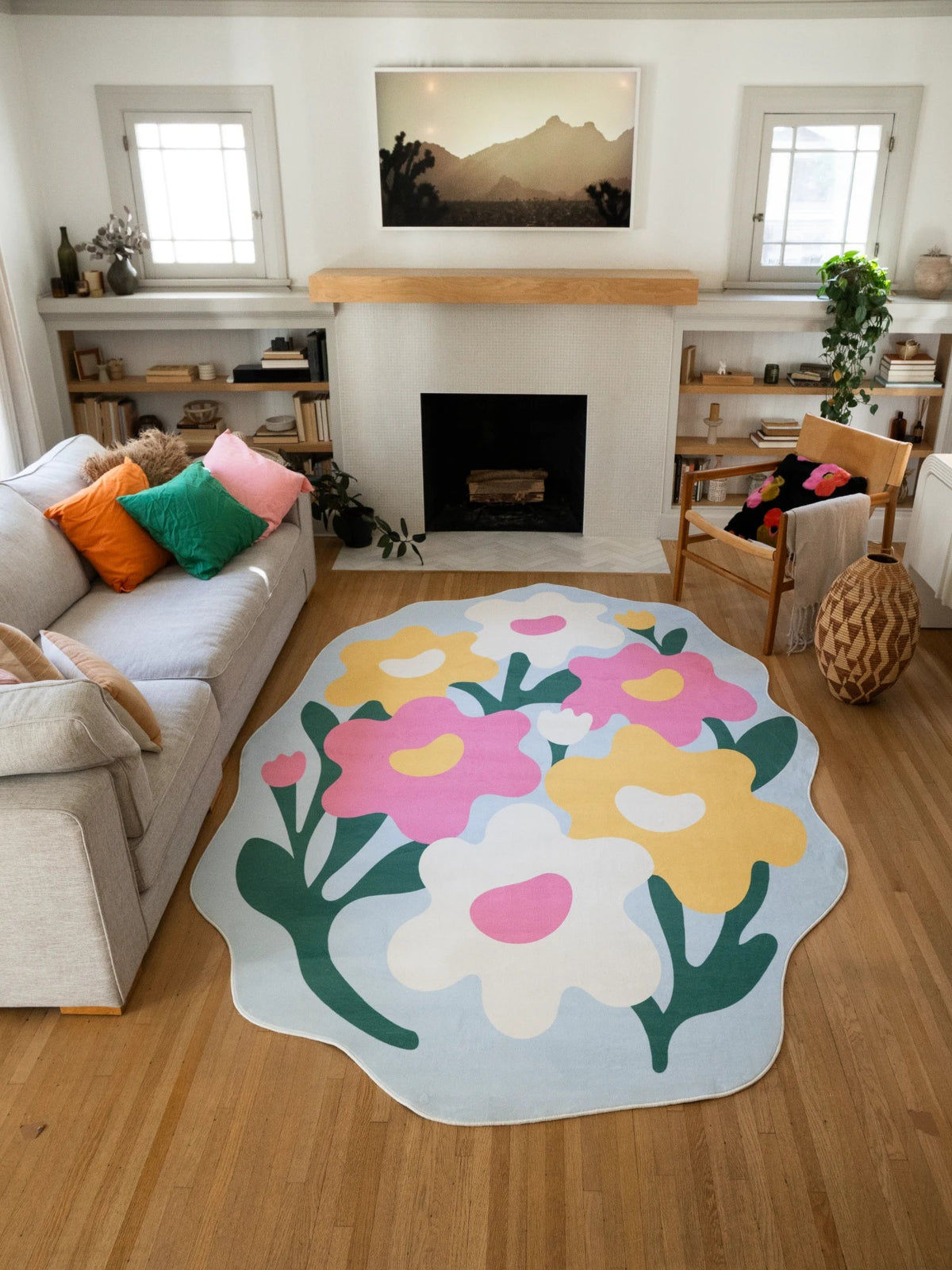 Floral area rug in front of the fireplace, showing hand cut style flower shapes and dark green stems on a pale blue ground