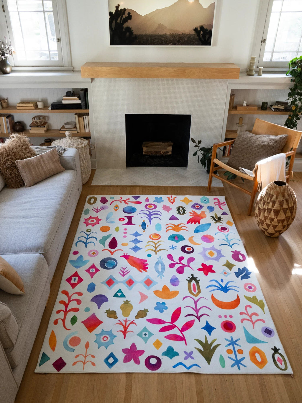 Graphic pattern rug in front of the fireplace, with a white ground covered in colorful flowers, moons, birds, and abstract icons