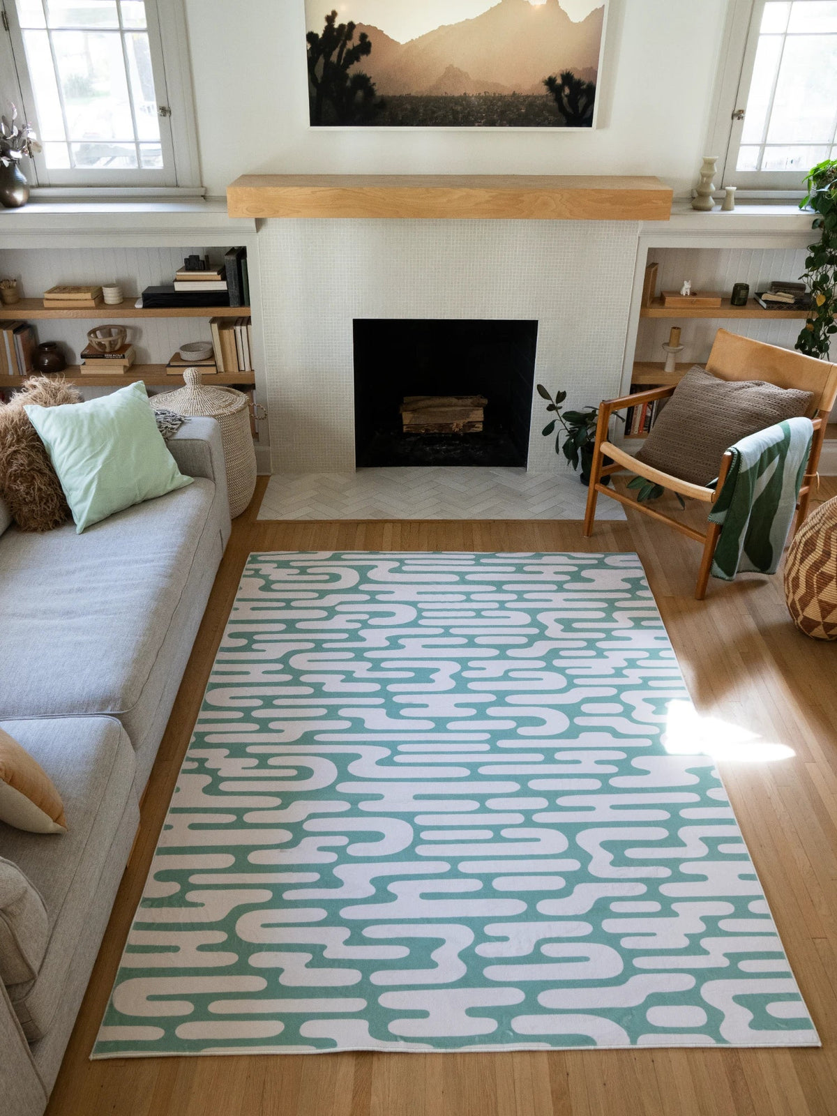 Green Abstract Wavy Area Rug in a sunlit modern living room with a fireplace, cream sofa, wood chair, and open shelving