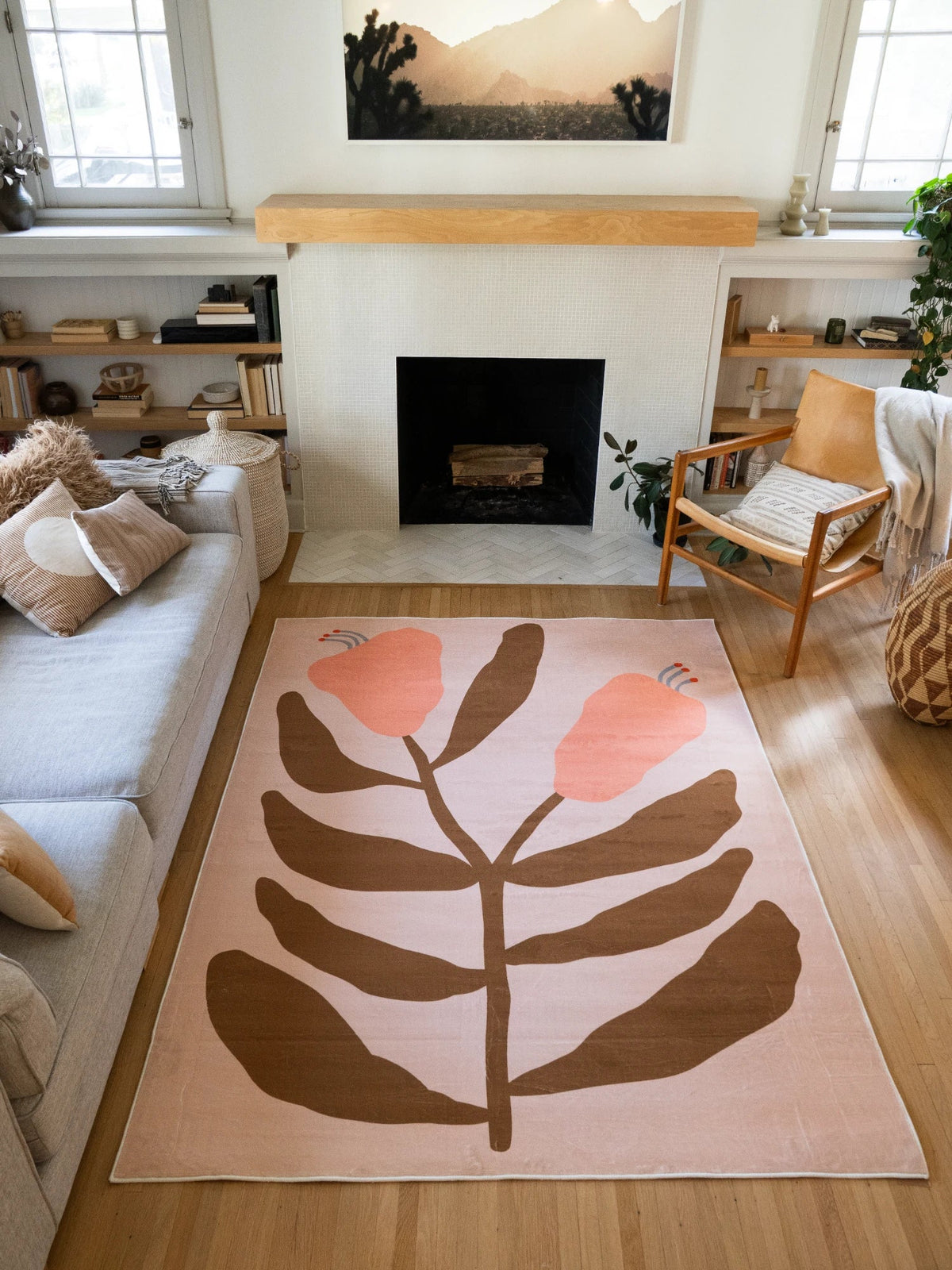 Beige Vintage Flower Rug by Sophie Deller in a sunlit living room with a fireplace, neutral sofa, and wood accent chair