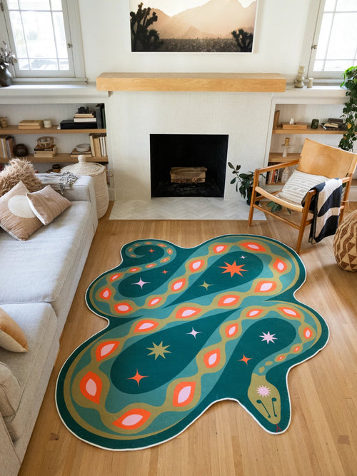Deep green abstract snake rug centered between the sofa and fireplace on a light wood floor in a bold living room