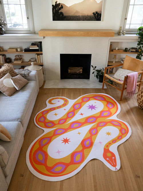 Warm orange abstract snake rug laid in front of the fireplace, with winding curves and eye like spots