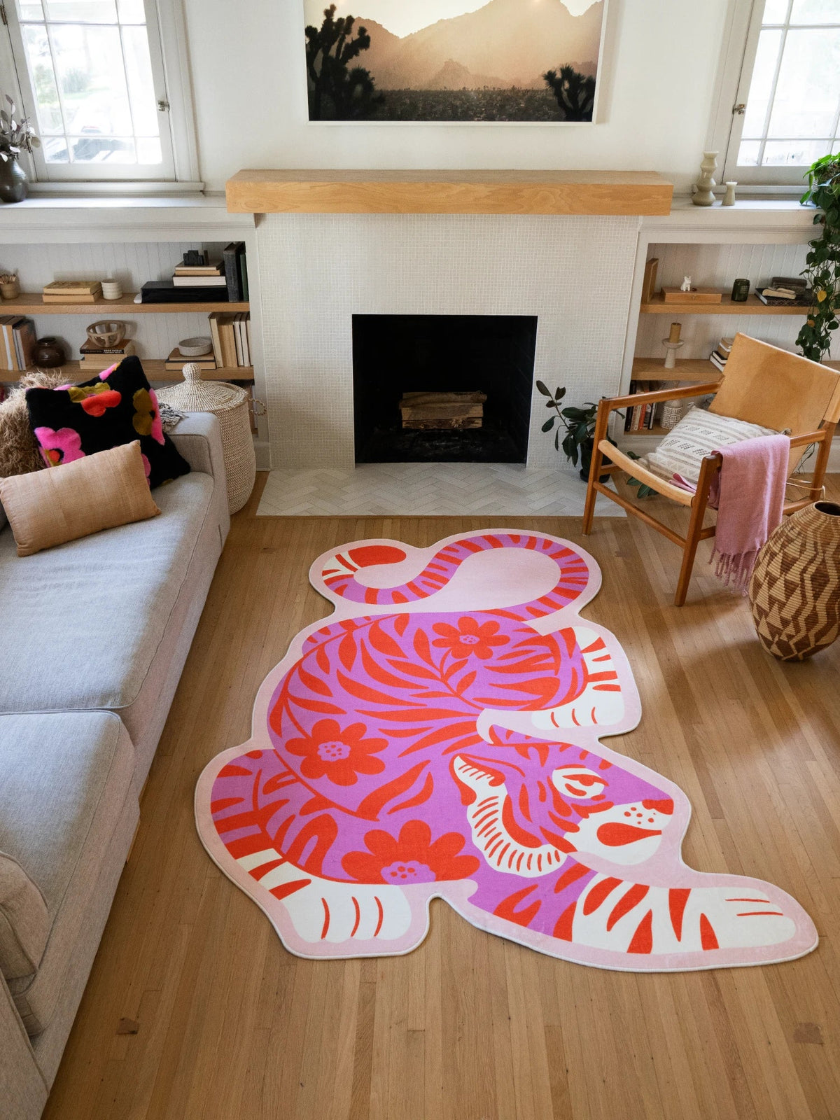 Pink vintage tiger shaped rug centered on a light wood floor between the sofa and fireplace in a bold living room