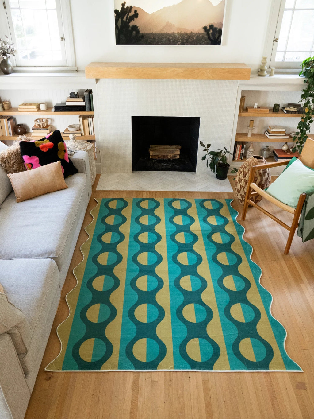 Green and mustard geometric striped area rug centered between the sofa and fireplace on a light wood floor