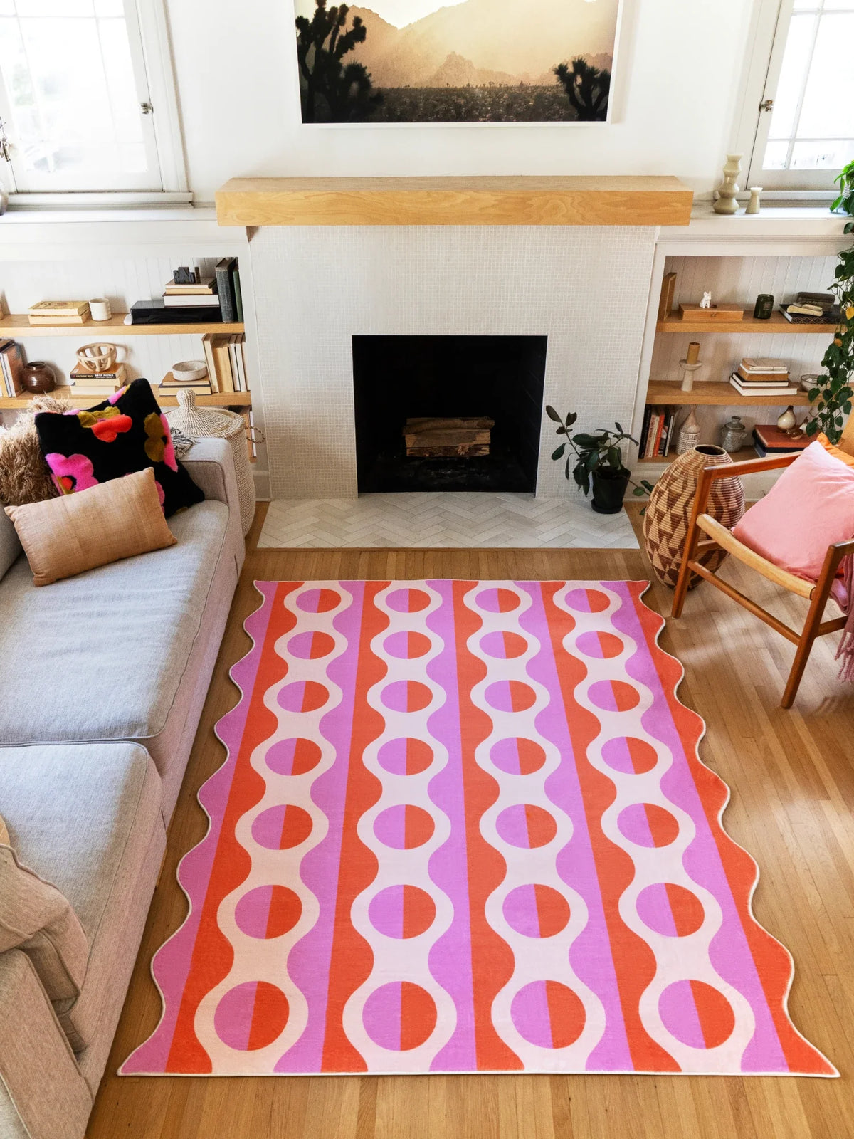 Pink and orange geometric striped rug laid in front of the fireplace, with repeating oval bands across the surface