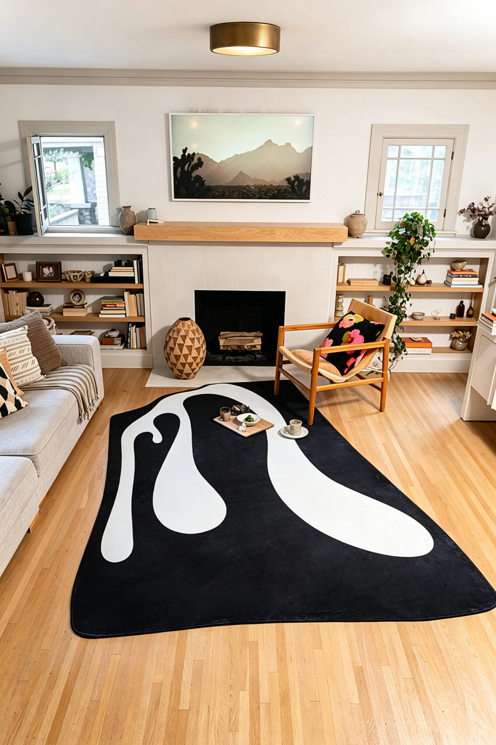 From the room entrance, the black and white rug extends toward the fireplace with seating arranged on both sides.