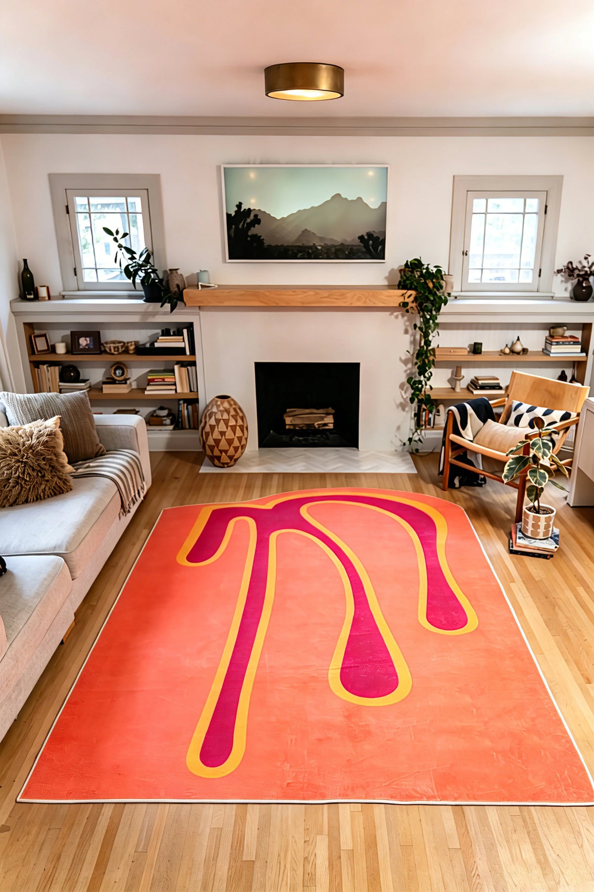7' × 9' Orange Melting Abstract Art Rug by Ariana Berman between a gray sofa and wooden armchair facing a fireplace.