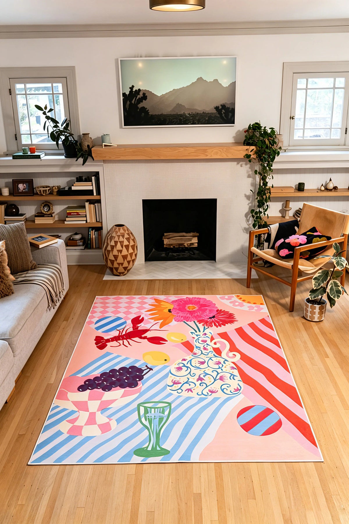 5' × 7' colorful rug with pink, red, and blue stripes, fruit, flowers, and a lobster centered in front of a fireplace.