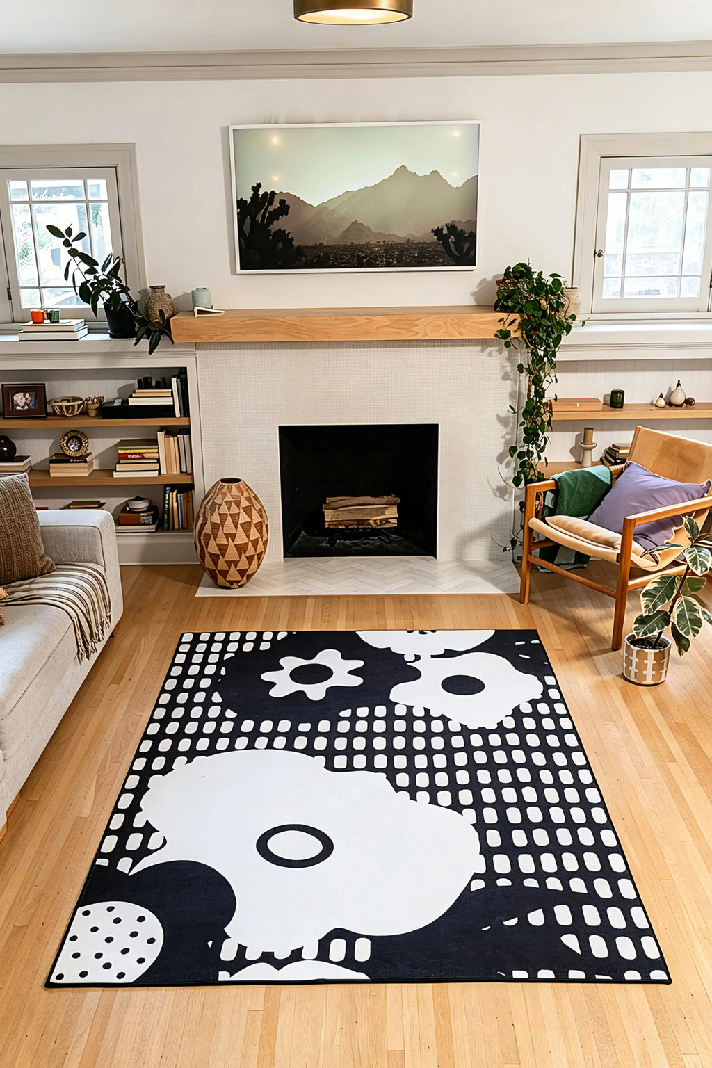 5' × 7' black rug with white flower silhouettes, circles, and rows of rounded rectangular marks in front of a fireplace.