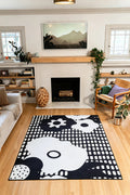 5' × 7' black rug with white flower silhouettes, circles, and rows of rounded rectangular marks in front of a fireplace.