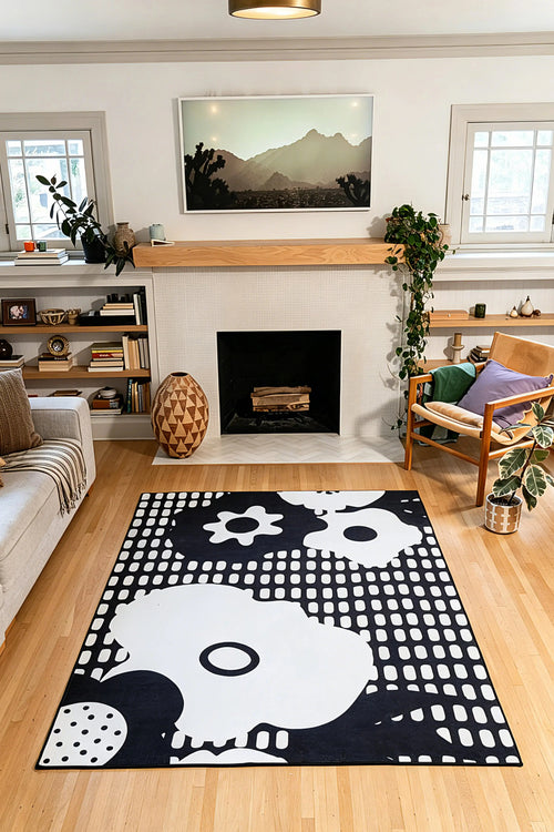 5' × 7' black rug with white flower silhouettes, circles, and rows of rounded rectangular marks in front of a fireplace.