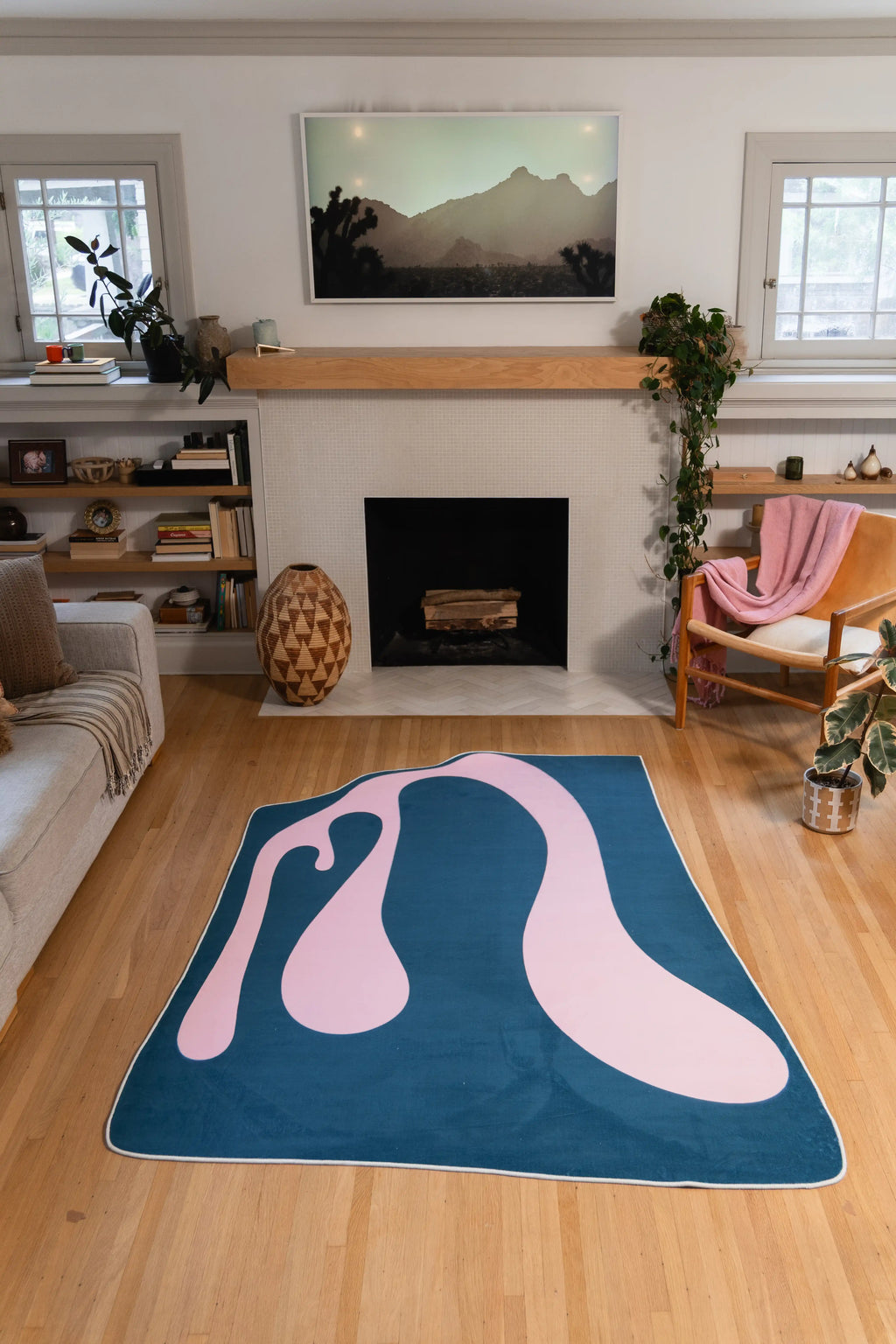 The 5' × 7' blue and pink version sits in front of the fireplace with the surrounding wood floor visible.