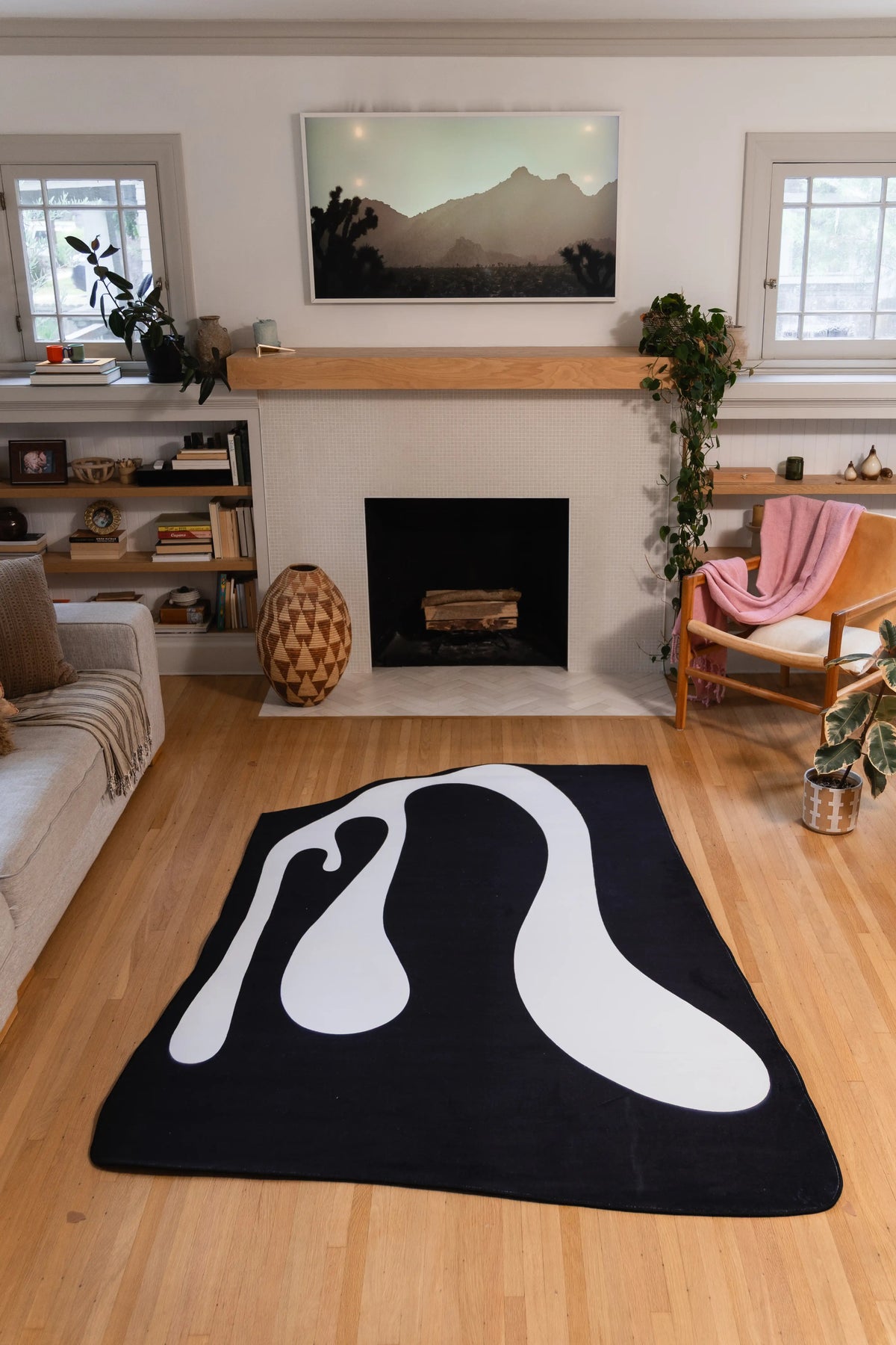White ribbon shapes curve across a 5' × 7' black rug placed in front of a fireplace.