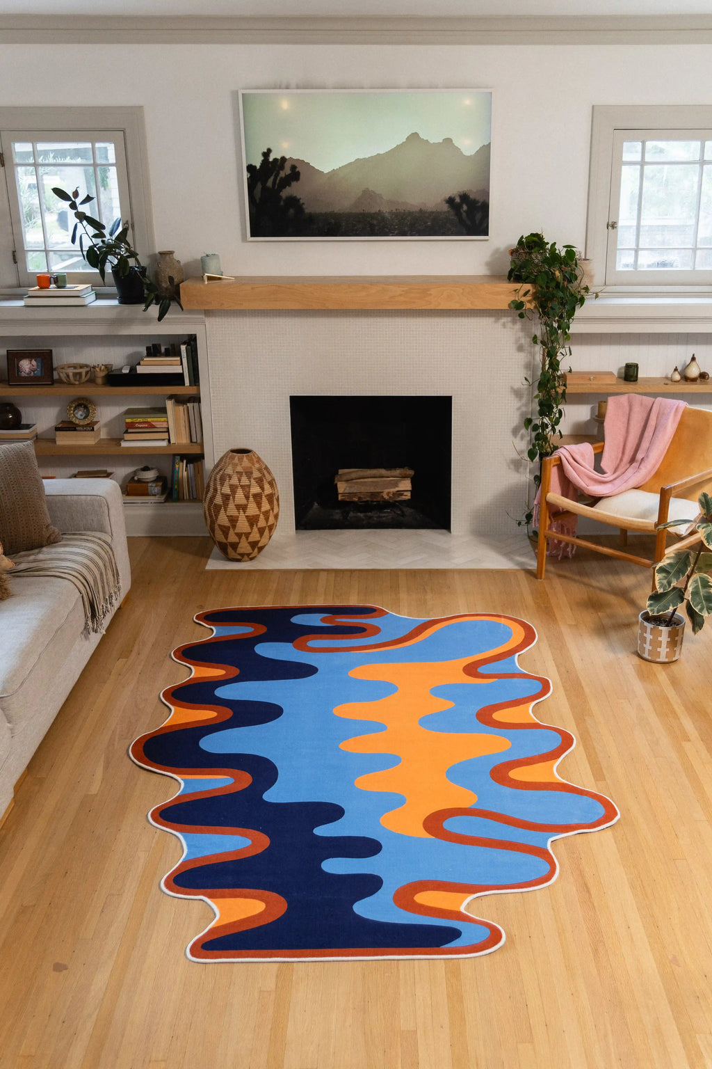A 5' × 7' blue and orange rug with a rippling edge sits centered in front of a fireplace.