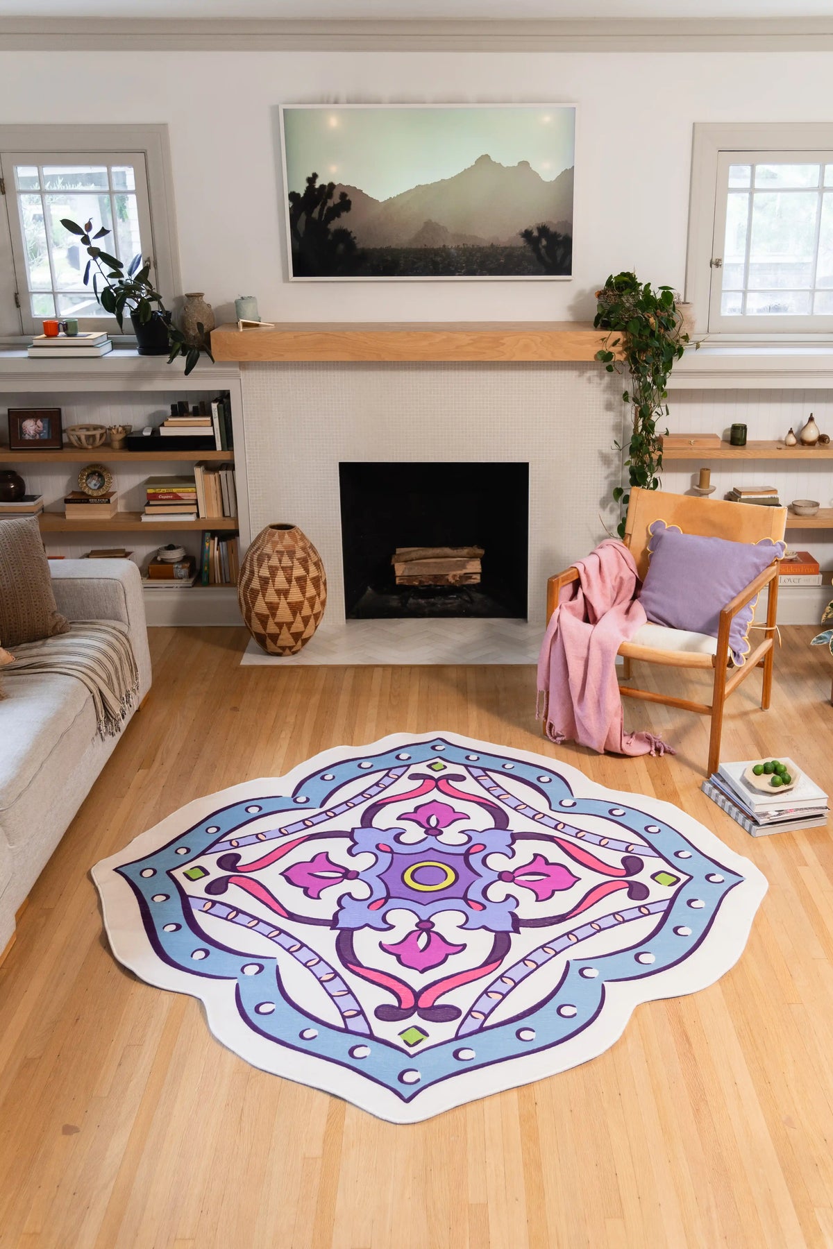 Multicolor Vintage Medallion Rug by Maayan Alper-Swan on wood floor in front of a fireplace, between a sofa and chair.