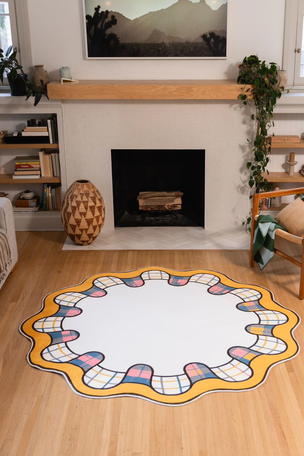 6' × 6' Yellow Scalloped Plaid Border Rug by Ariana Berman with a cream center, golden wavy rim, and multicolor plaid loops in front of a fireplace.