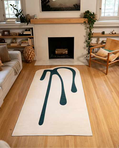 4' × 9' beige drip-pattern rug centered on light wood flooring in front of a black fireplace.