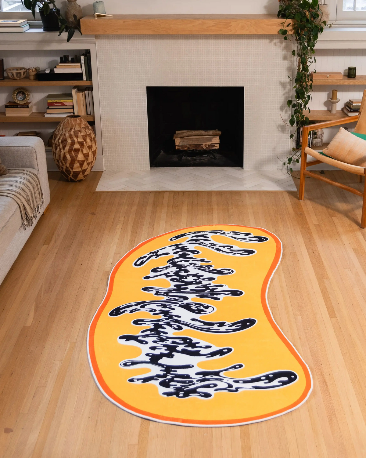 A 4' × 7' Yellow Swirl Abstract Rug by Ariana Berman rests in front of a fireplace, its freeform orange border exposed on the wood floor.