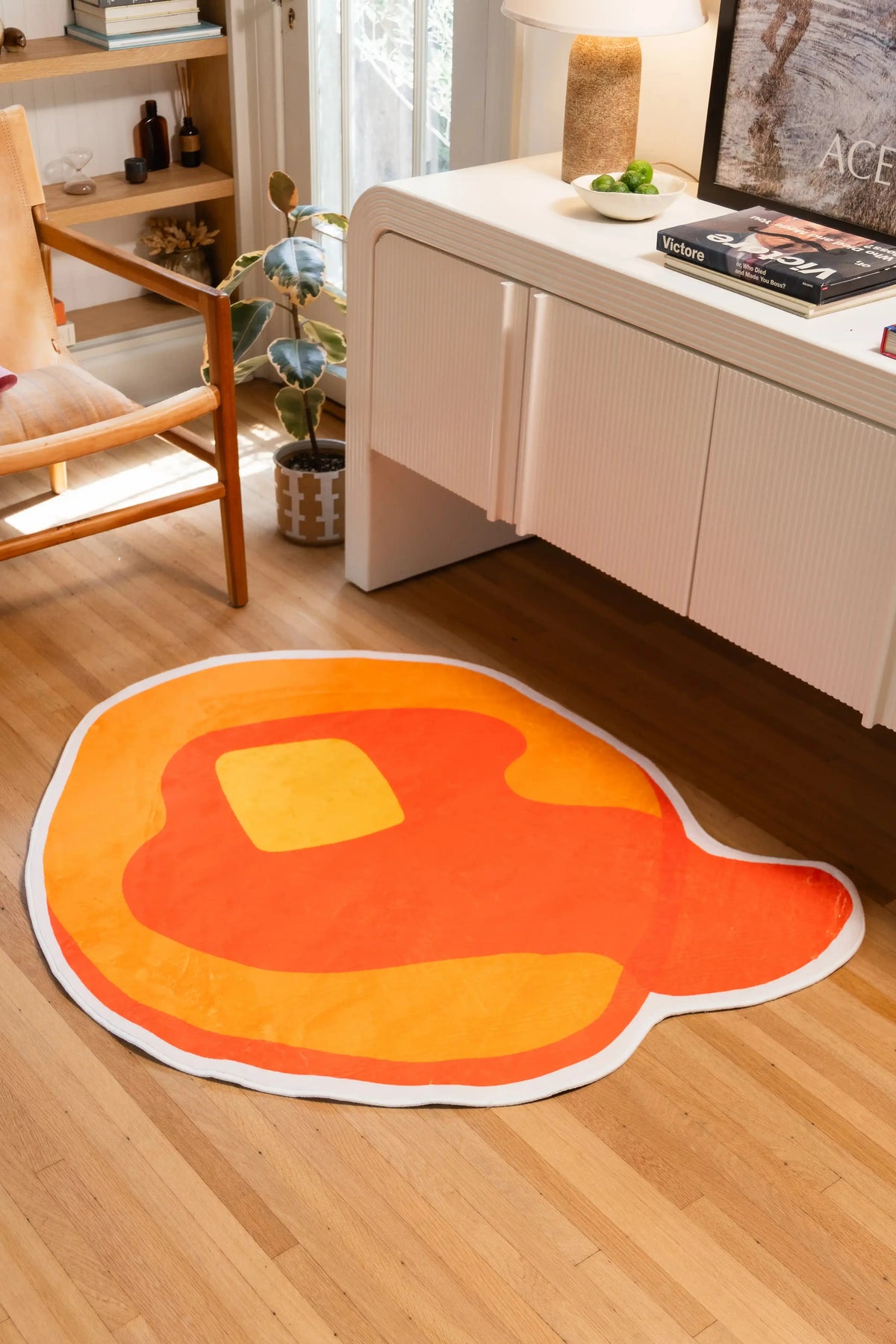 4' × 4' Yellow Irregular Pancake Rug by Becca Franks with orange syrup, a yellow butter square, and white border beside a white cabinet.