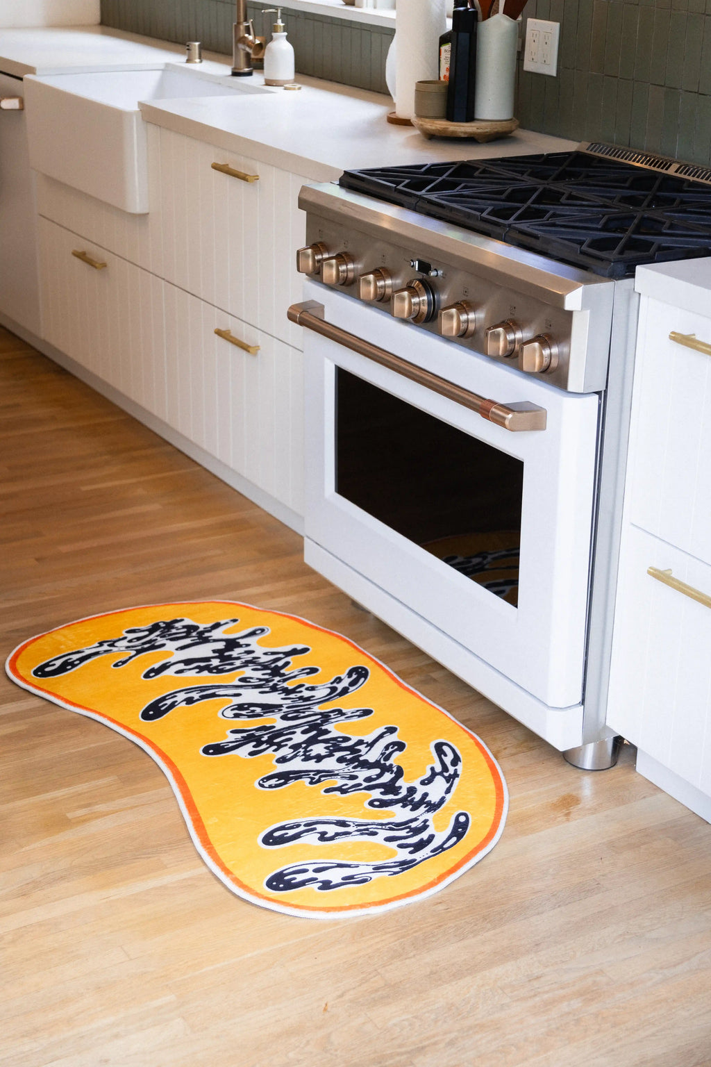 The runner sits at an angle to the oven, with its bright orange binding standing out against the wood floor.
