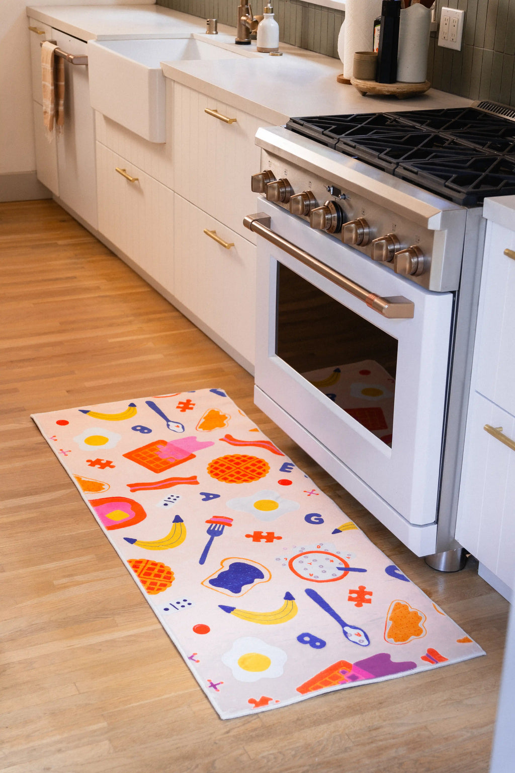 2' × 5' Multicolor Playful Waffle and Egg Runner Rug by Becca Franks placed in front of a white oven on a wood floor.