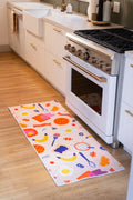 2' × 5' Multicolor Playful Waffle and Egg Runner Rug by Becca Franks placed in front of a white oven on a wood floor.