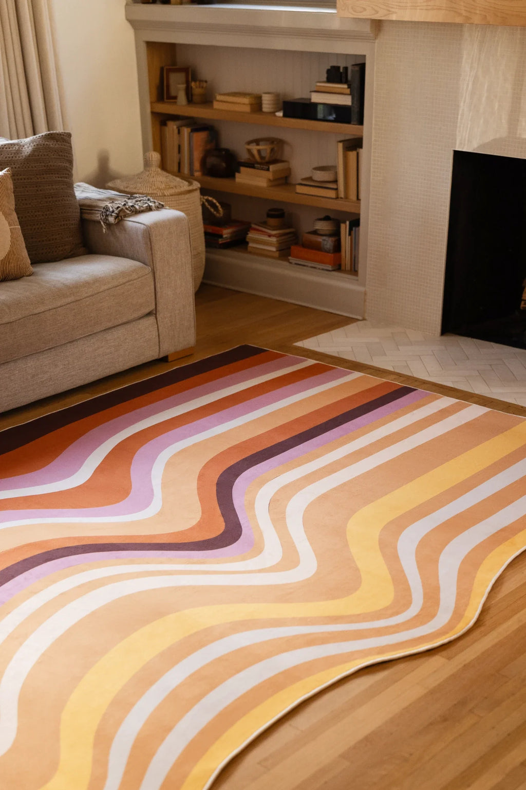 Warm neutral area rug with geological stripe forms in front of built in shelving and a beige sofa