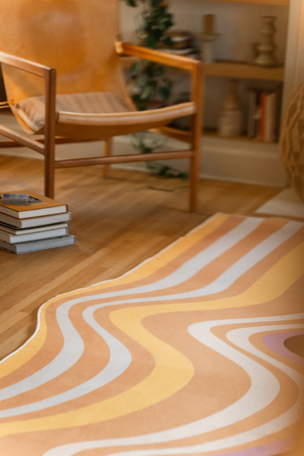 Vertical crop of the rug beside a wood chair and books, showing ribbon like stripes in warm earth tones