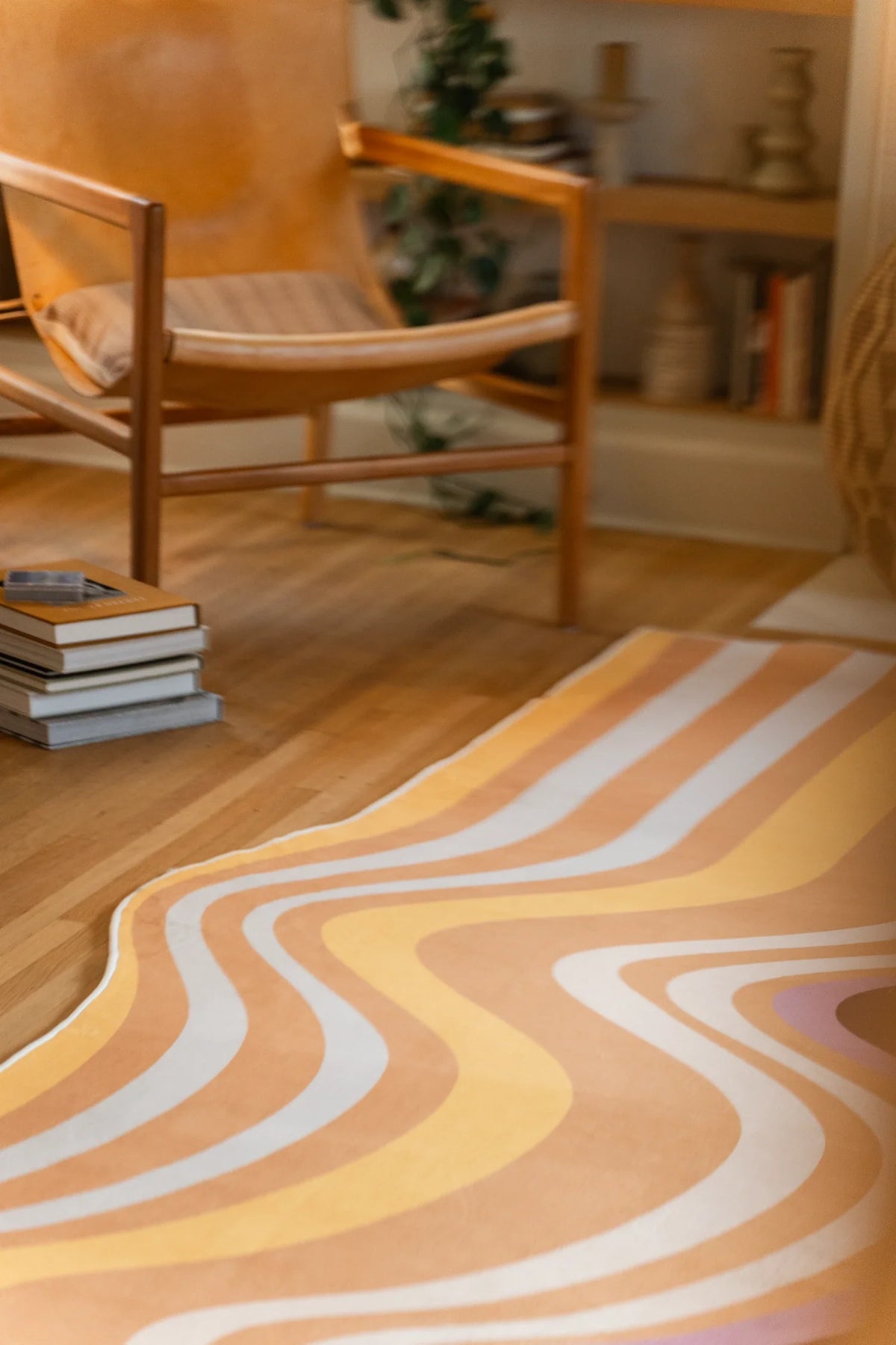 Vertical crop of the rug beside a wood chair and books, showing ribbon like stripes in warm earth tones