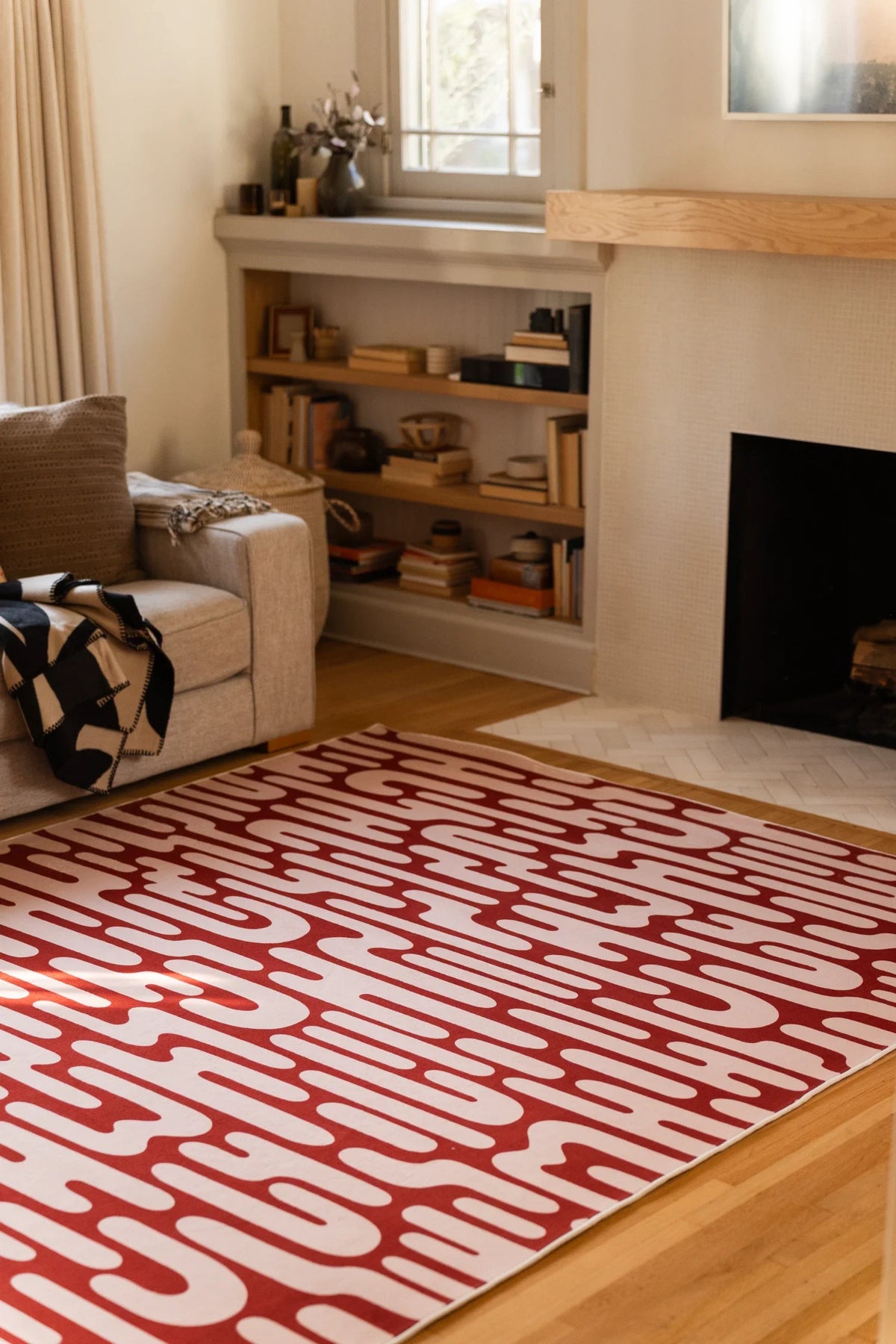 Brown Abstract Wavy Area Rug near a fireplace and open shelving in a soft toned modern interior