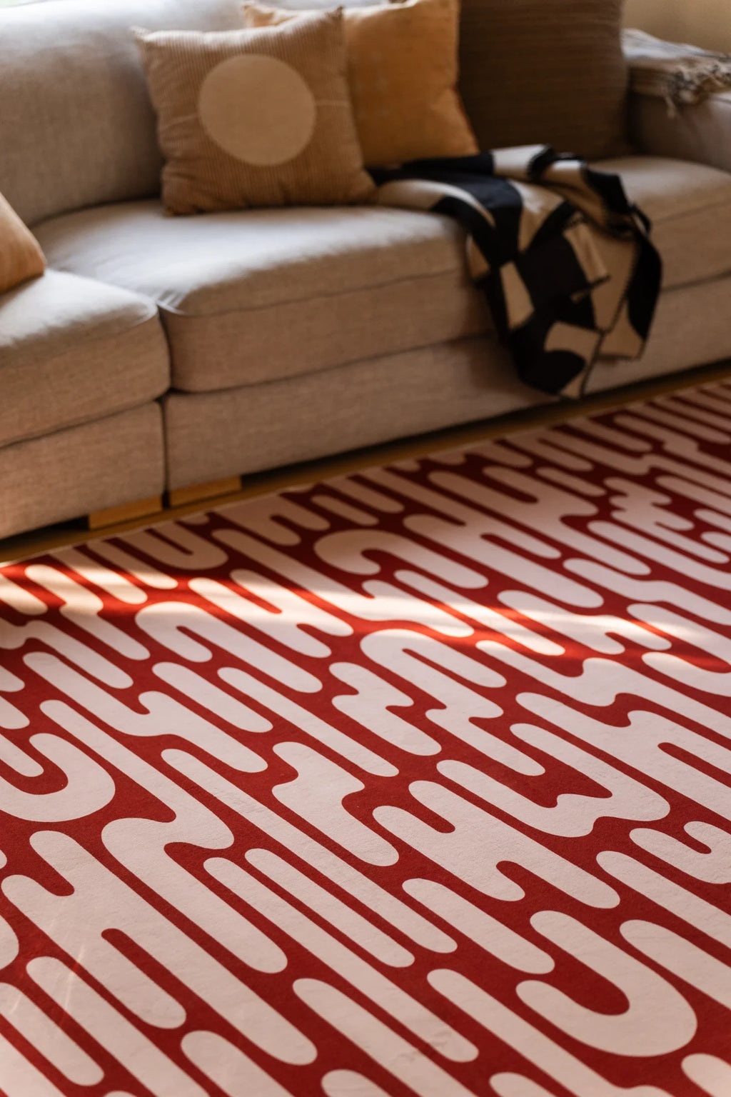 Close view of the brown Abstract Wavy Area Rug beneath a sofa edge in a casual modern living room