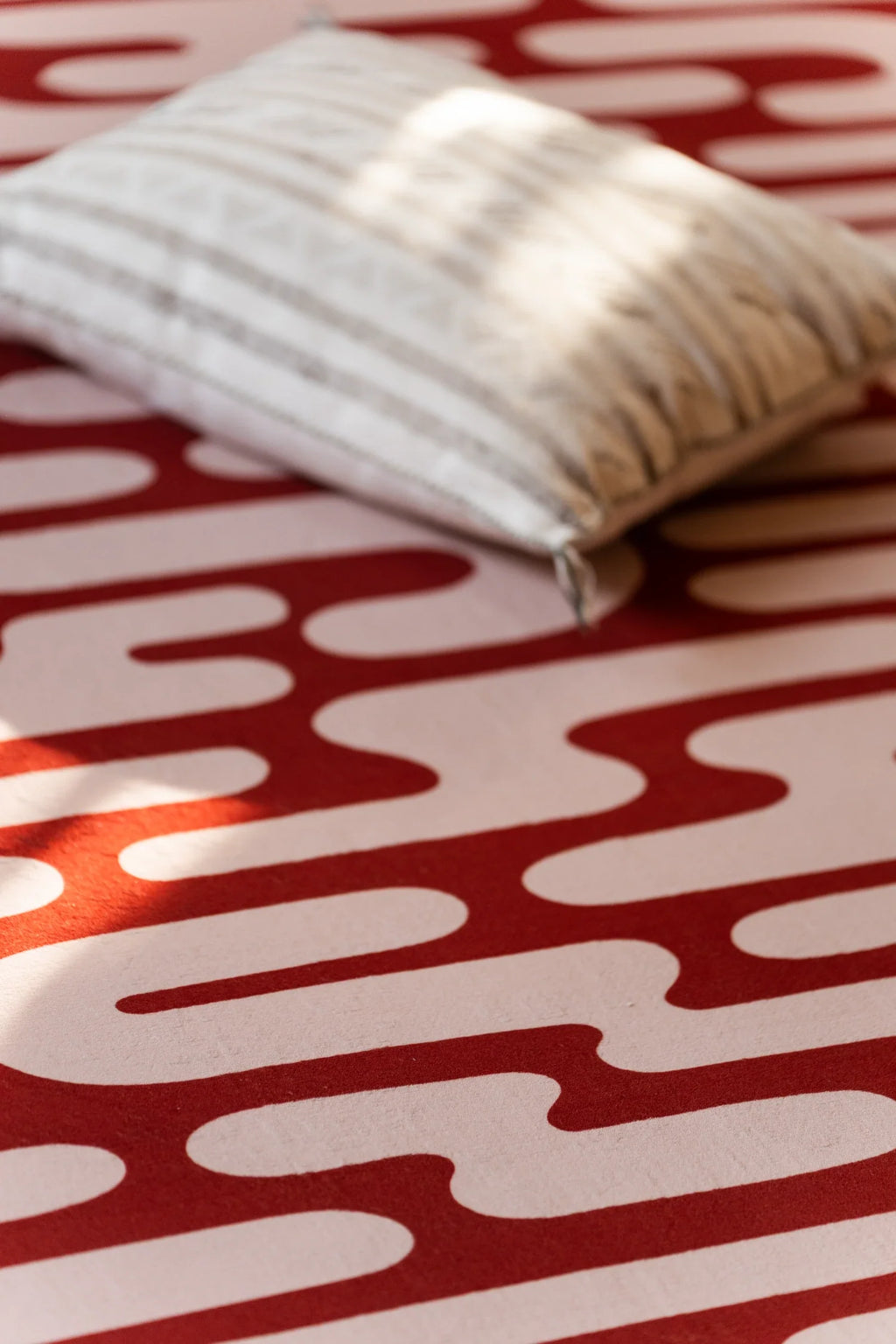 Close view of the brown Abstract Wavy Area Rug with a striped pillow resting on one corner
