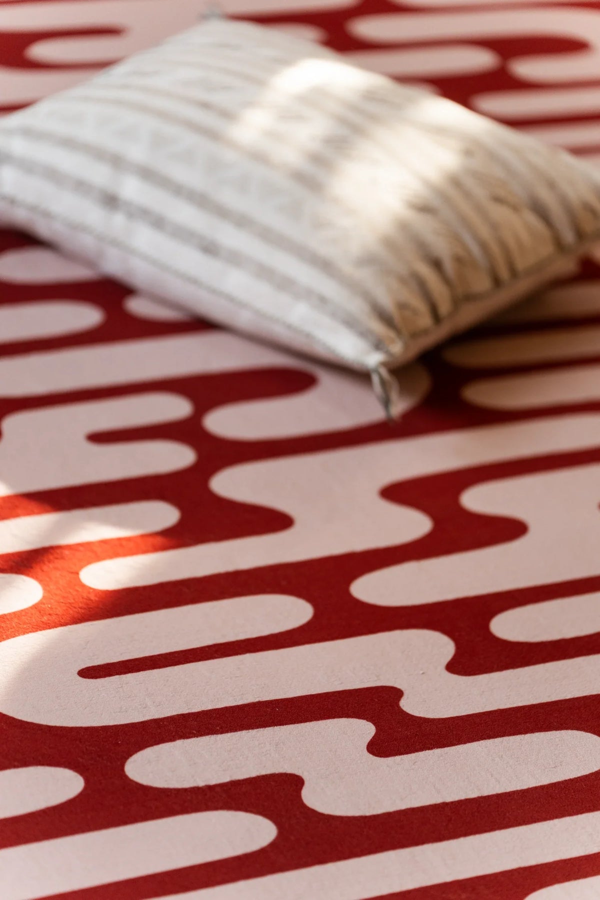 Close view of the brown Abstract Wavy Area Rug with a striped pillow resting on one corner