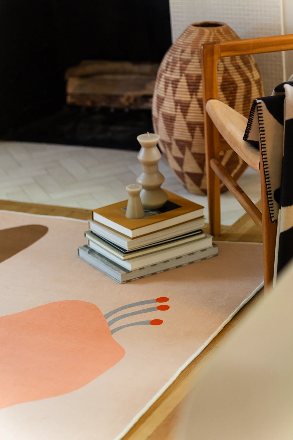 Corner detail near the fireplace and stacked books, with a peach flower head and soft beige border on the floor