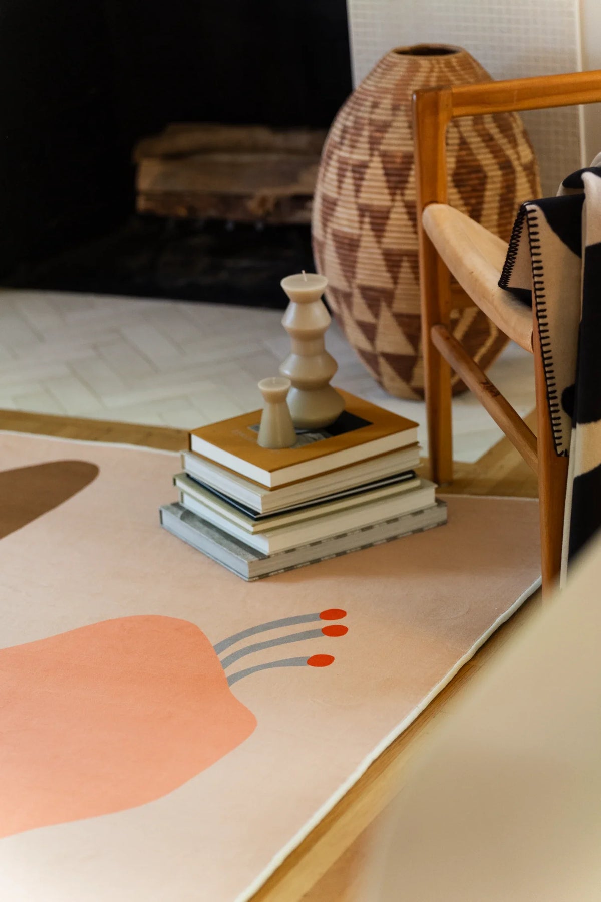 Corner detail near the fireplace and stacked books, with a peach flower head and soft beige border on the floor