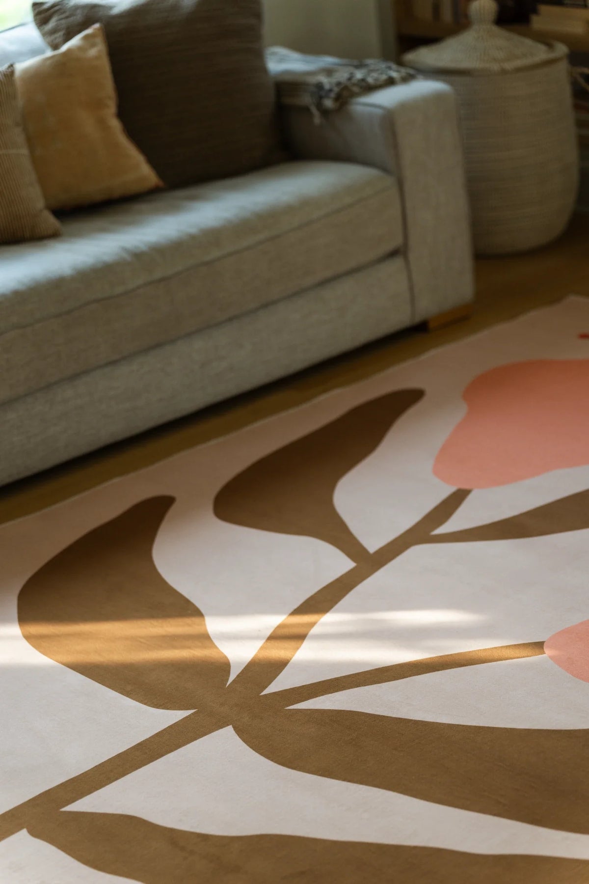 Close up of the floral area rug under a sofa edge, highlighting curved brown stems and a pale peach flower head