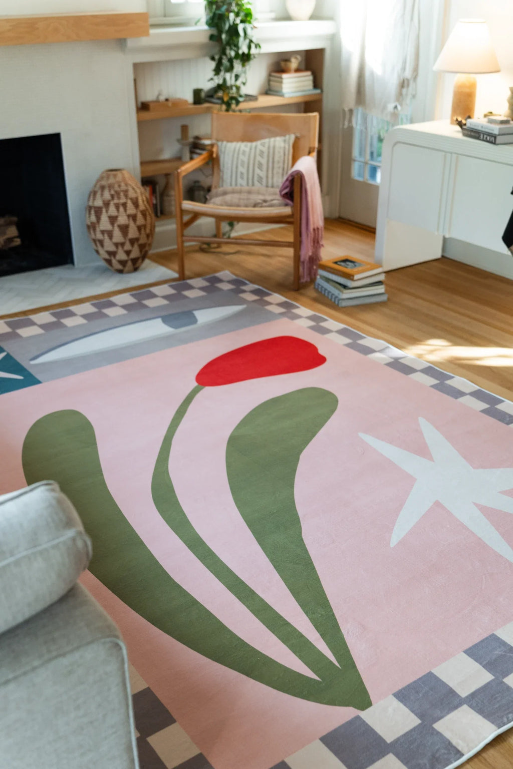 Partial view near the sofa and fireplace, showing the blush pink rug with curved olive stems and a white floral star