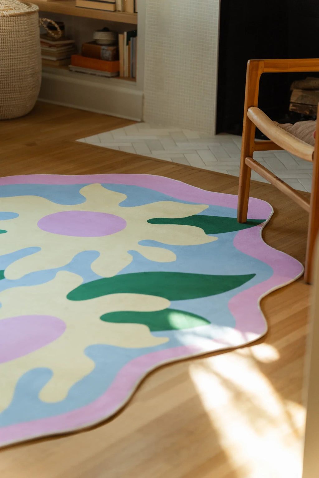 Close crop near the fireplace, highlighting the rug's wavy pink border and layered green botanical shapes