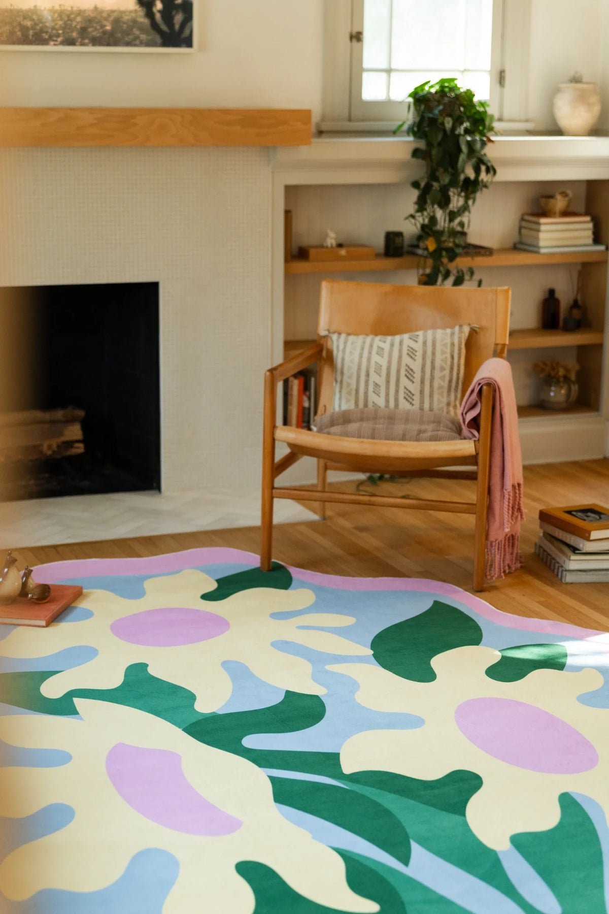 Wavy flower area rug beside a wood chair and open shelving, with layered pastel petals on a light wood floor