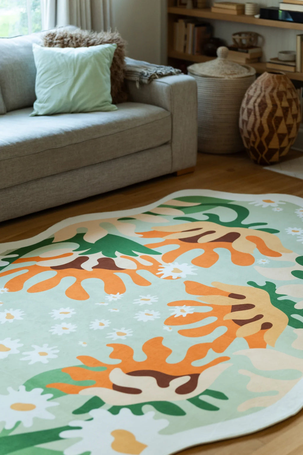 Irregular floral area rug near a wood chair, with sunlight across the cream border and layered garden shapes