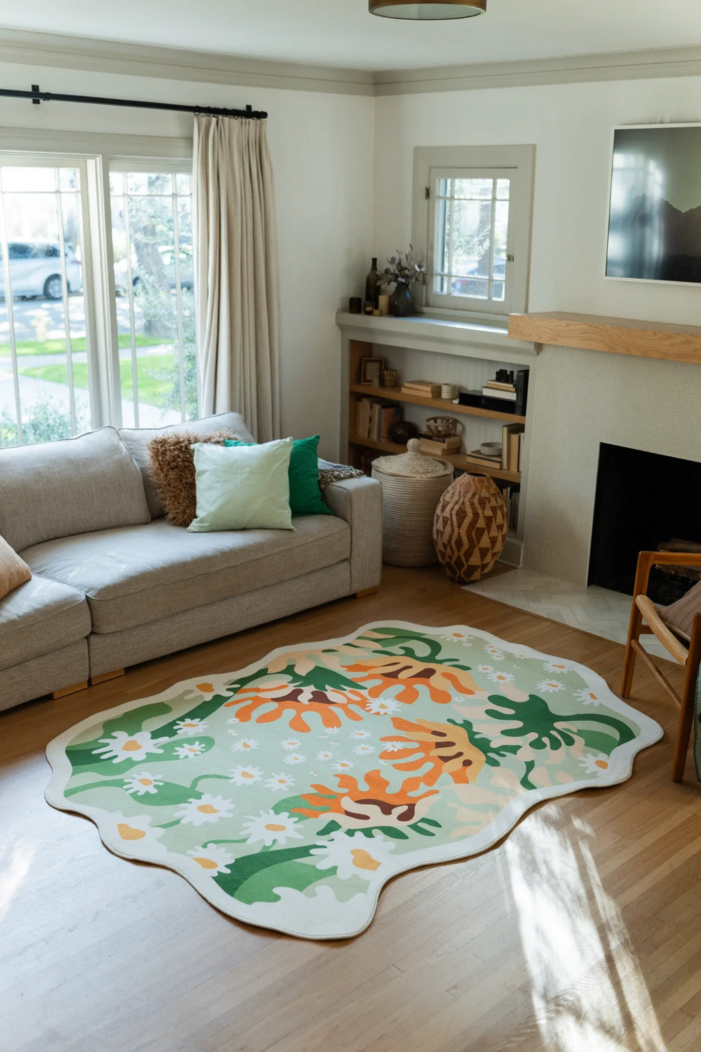 Soft green abstract floral rug beside a neutral sofa in a bright living room, showing orange petals and white daisies