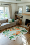 Soft green abstract floral rug beside a neutral sofa in a bright living room, showing orange petals and white daisies