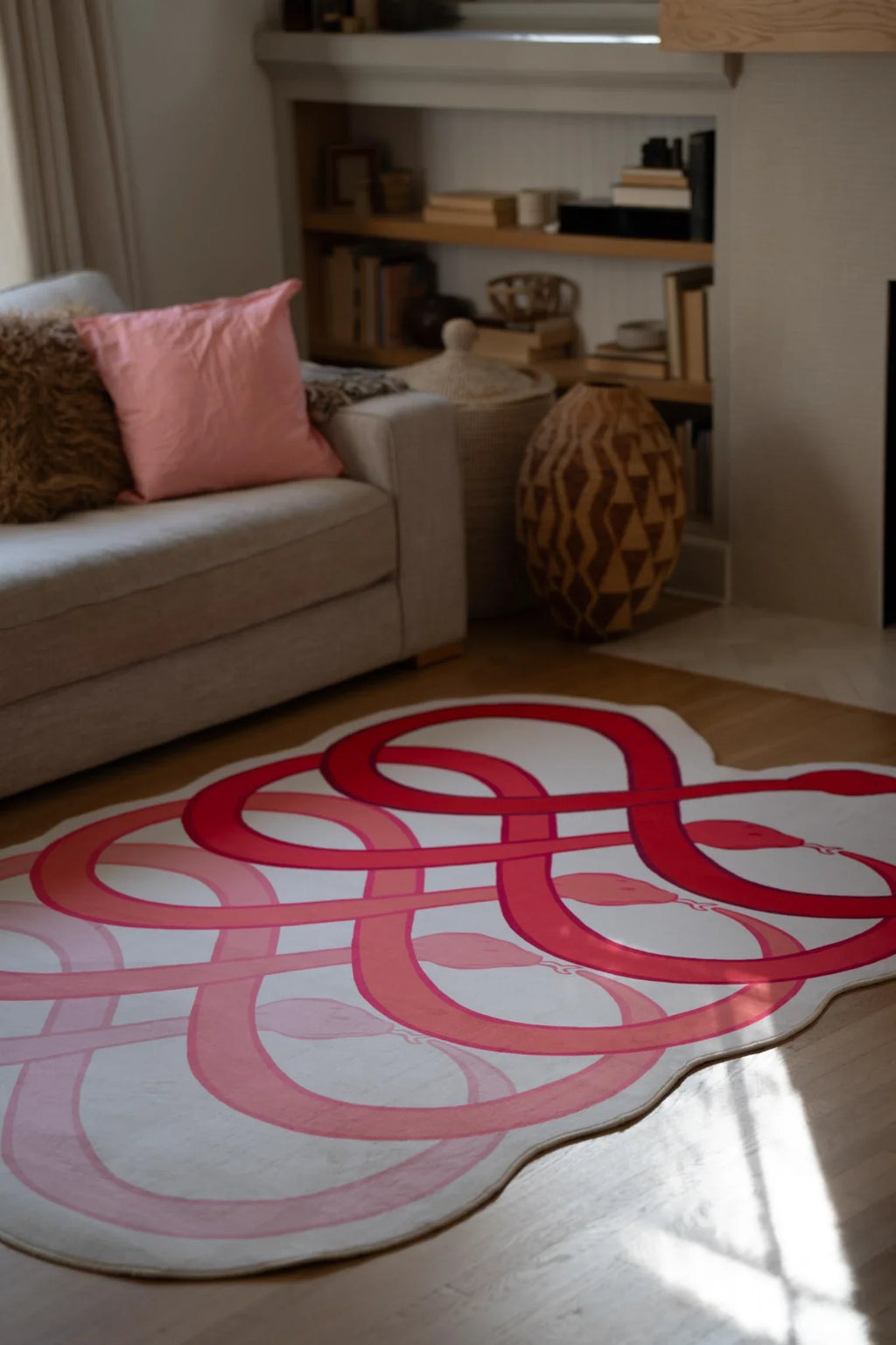 Abstract loop area rug beside a beige sofa, with red and blush curves spread across the living room floor