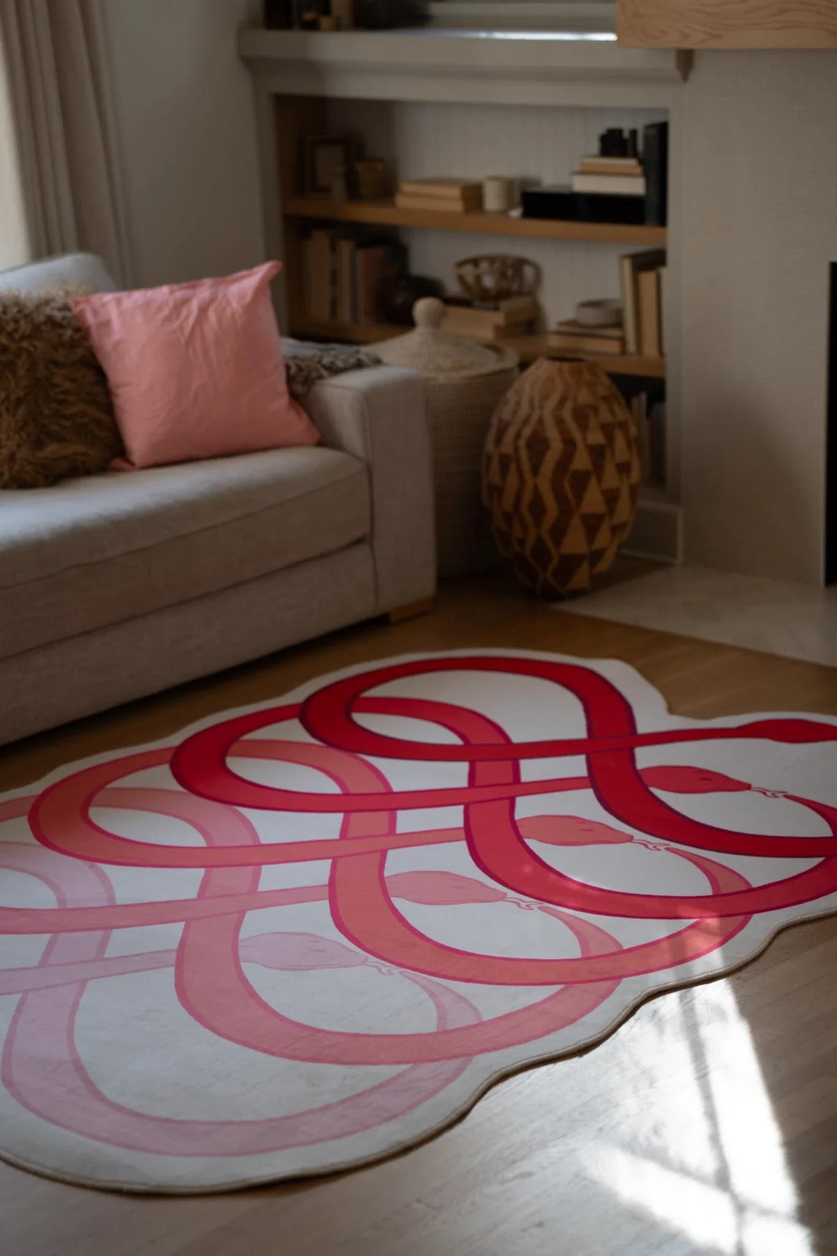 Abstract loop area rug beside a beige sofa, with red and blush curves spread across the living room floor