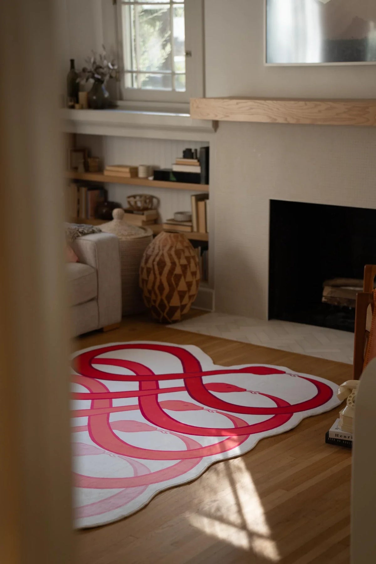 Red loop snake rug in front of the fireplace, showing layered curved bands on a white ground
