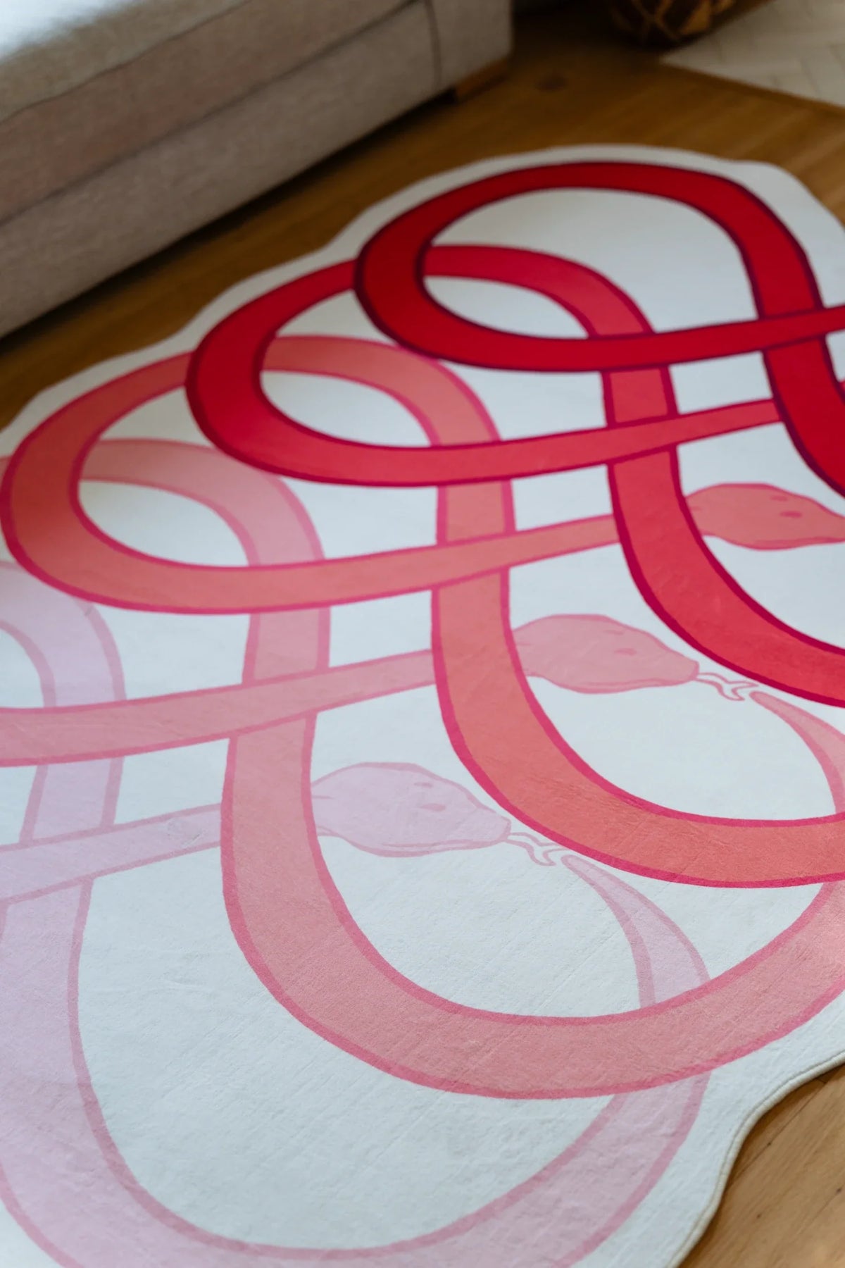 Partial view of the red abstract rug beneath the sofa edge, with repeated loop forms across the surface