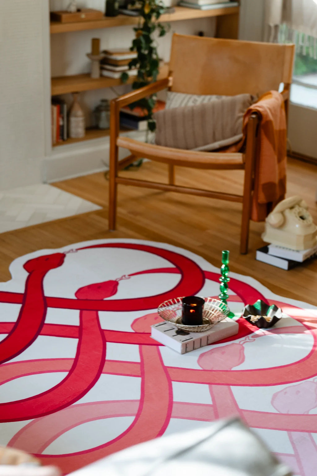 Red graphic rug beside a wood chair in the living room, with layered loop shapes and a white base