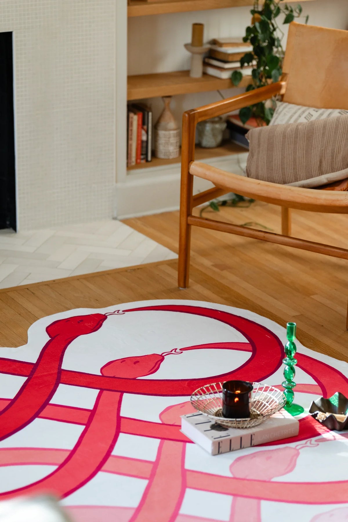 Living room rug detail near a wood chair and tray, showing interwoven red curves on a white field